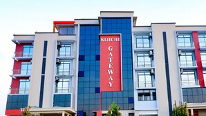 A multi-story building with a prominent red and blue facade, featuring balconies and air conditioning units. - Kijichi Gateway Hotel (Dar es Salaam)