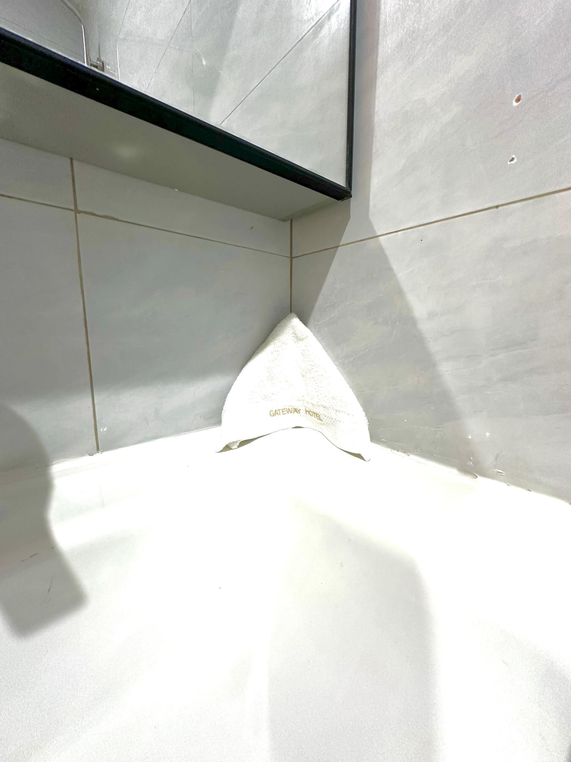 Una esquina con azulejos blancos y un estante negro.