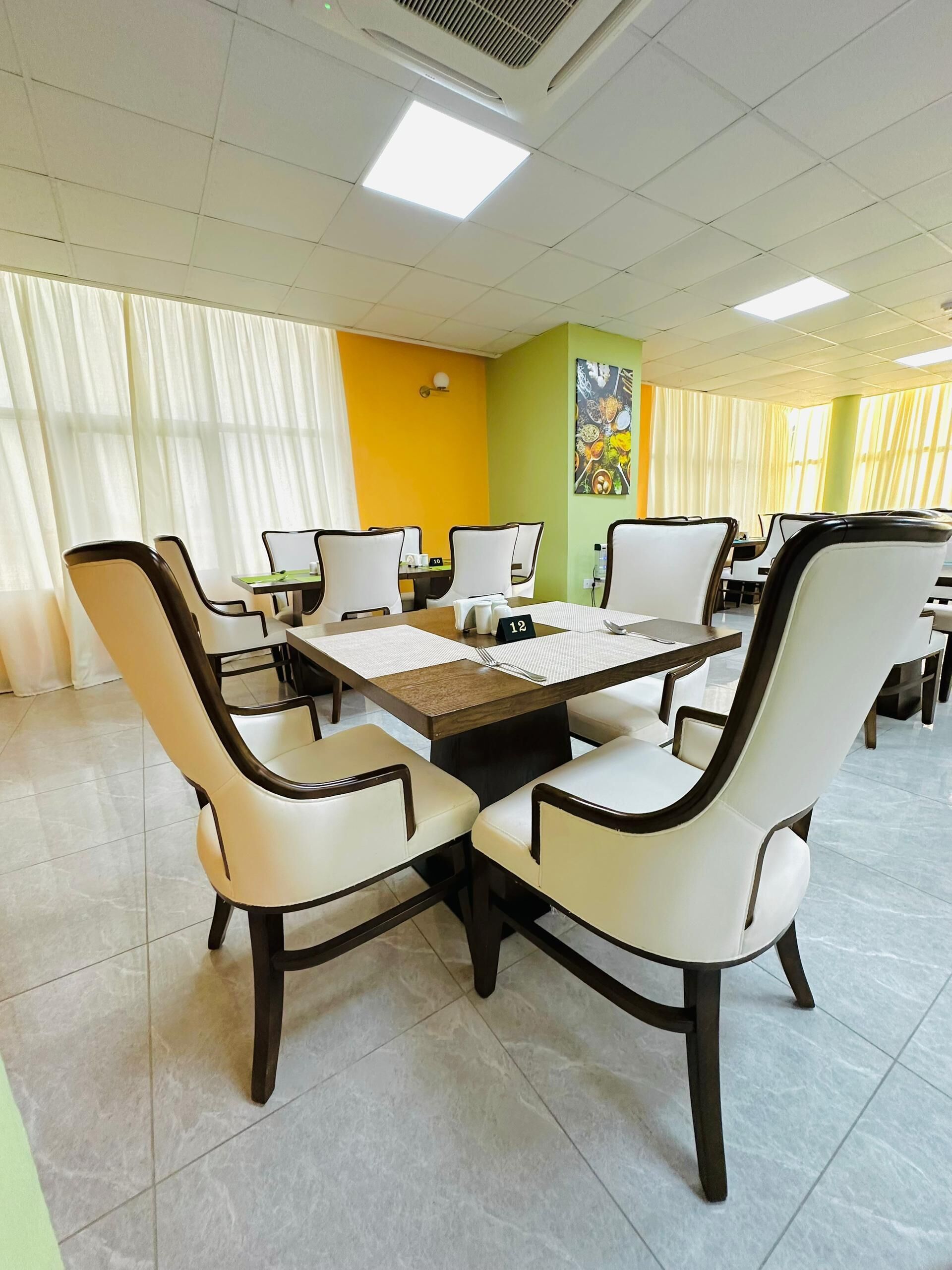 A conference room with a large table, white chairs, and a painting on the wall.
