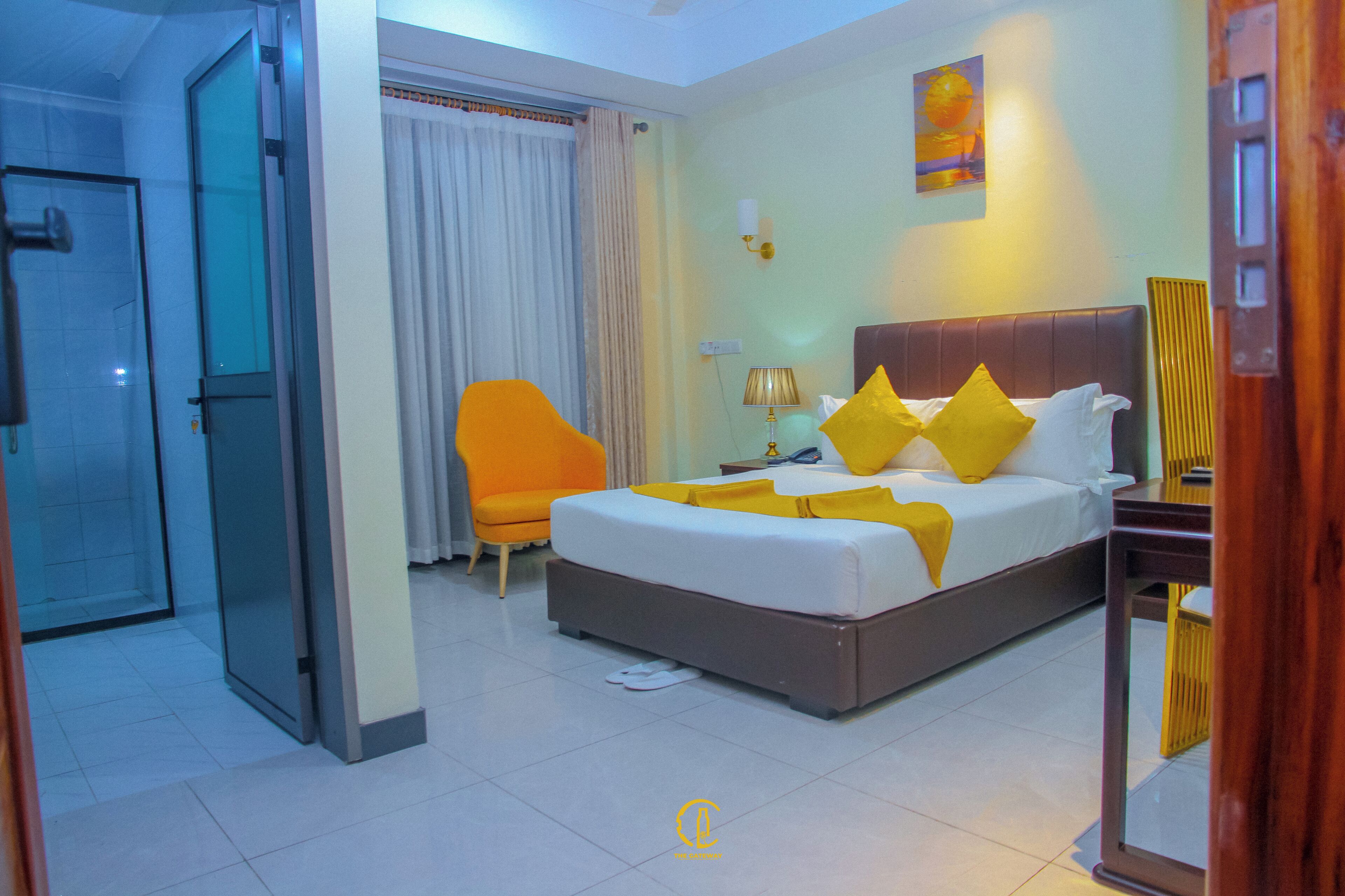 Ein Hotelzimmer mit Bett, Sessel, Nachttisch und Lampe.