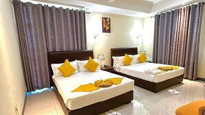 Une chambre d’hôtel avec deux lits, un ventilateur de plafond et un petit coin salon.