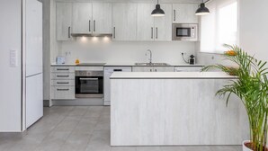 A modern kitchen with white cabinetry, stainless steel appliances, and a central island. - Costa Brava by Interhome (Salou)