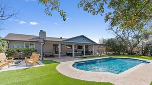 Un jardin avec une piscine, un patio couvert et une pelouse.