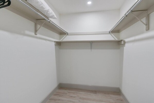 Un vestidor pequeño y vacío con paredes blancas y suelo de madera.