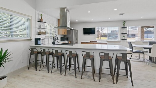 Une cuisine moderne dotée d’un îlot central, de tabourets de bar et d’un coin repas avec une table et des chaises.