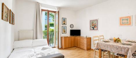 A hotel room with a bed, a desk, a dining table set for two, and a TV.