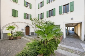 A courtyard with a building featuring arched doorways and green shutters.