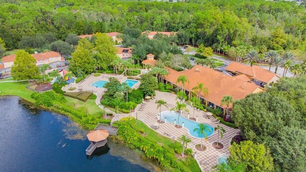 An aerial view of a resort with multiple swimming pools, a dock, and lush greenery.