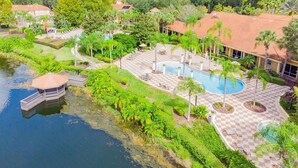 A resort with a swimming pool, palm trees, and a dock.