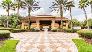 A hotel entrance with a checkered pathway, palm trees, and a sign reading 'ENCANTADA.'