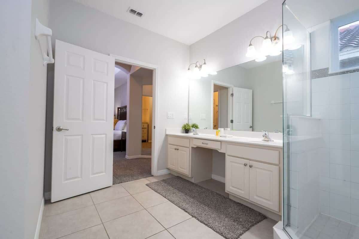 A modern bathroom with a walk-in shower, a large mirror, and a double vanity.