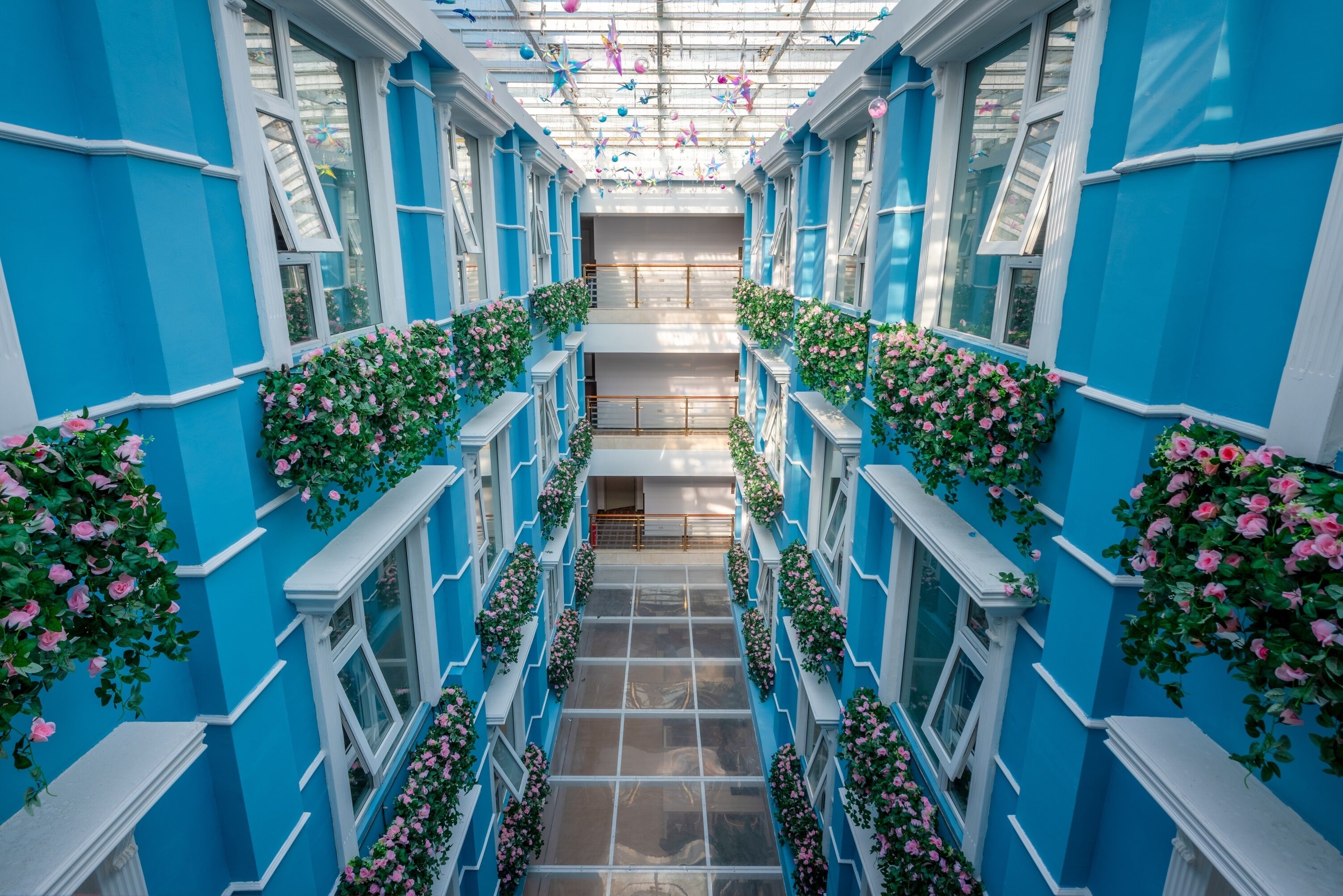 Un couloir aux murs bleus, aux boiseries blanches et orné de fleurs roses.