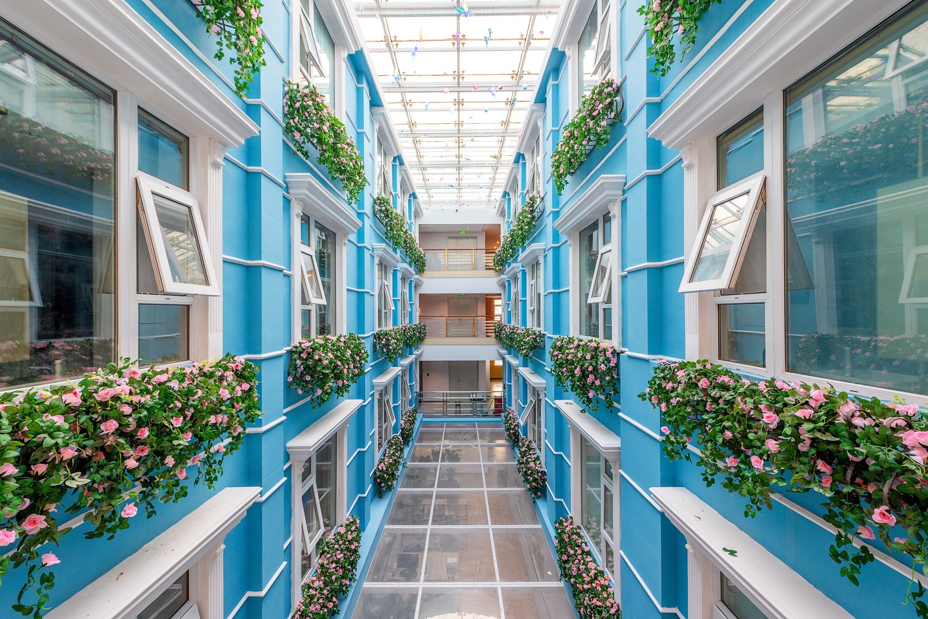Un couloir aux murs bleus, aux boiseries blanches et orné de fleurs roses.