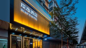 A hotel with a modern facade, large illuminated signage, and a visible entrance. - Huanyi Hotel  (Guangzhou)