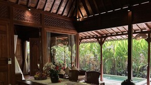 A wooden dining area with a table set for two, surrounded by chairs, under a wooden roof structure. - Darta Ubud Joglo Villa by EPS (Ubud)