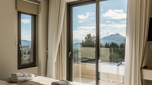 Une chambre d’hôtel avec un lit, une salle de bain et un balcon offrant une vue sur la montagne.