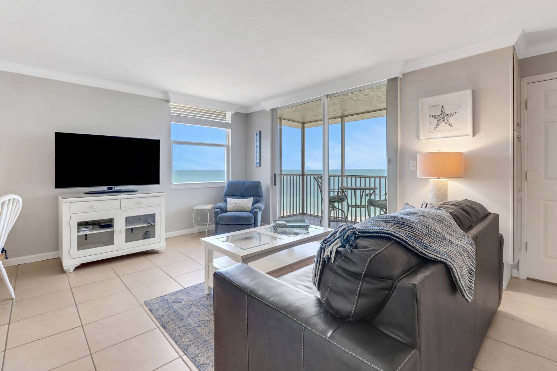Una sala de estar con televisor, sofá y balcón con vistas.