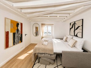 A bedroom with a bed, a bedside table, a mirror, and artwork on the walls.