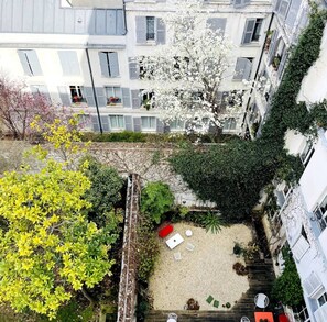 A courtyard with a small garden area, a white chair, and a red object.