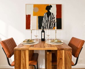 A dining table with four chairs, a wine bottle, and two glasses.