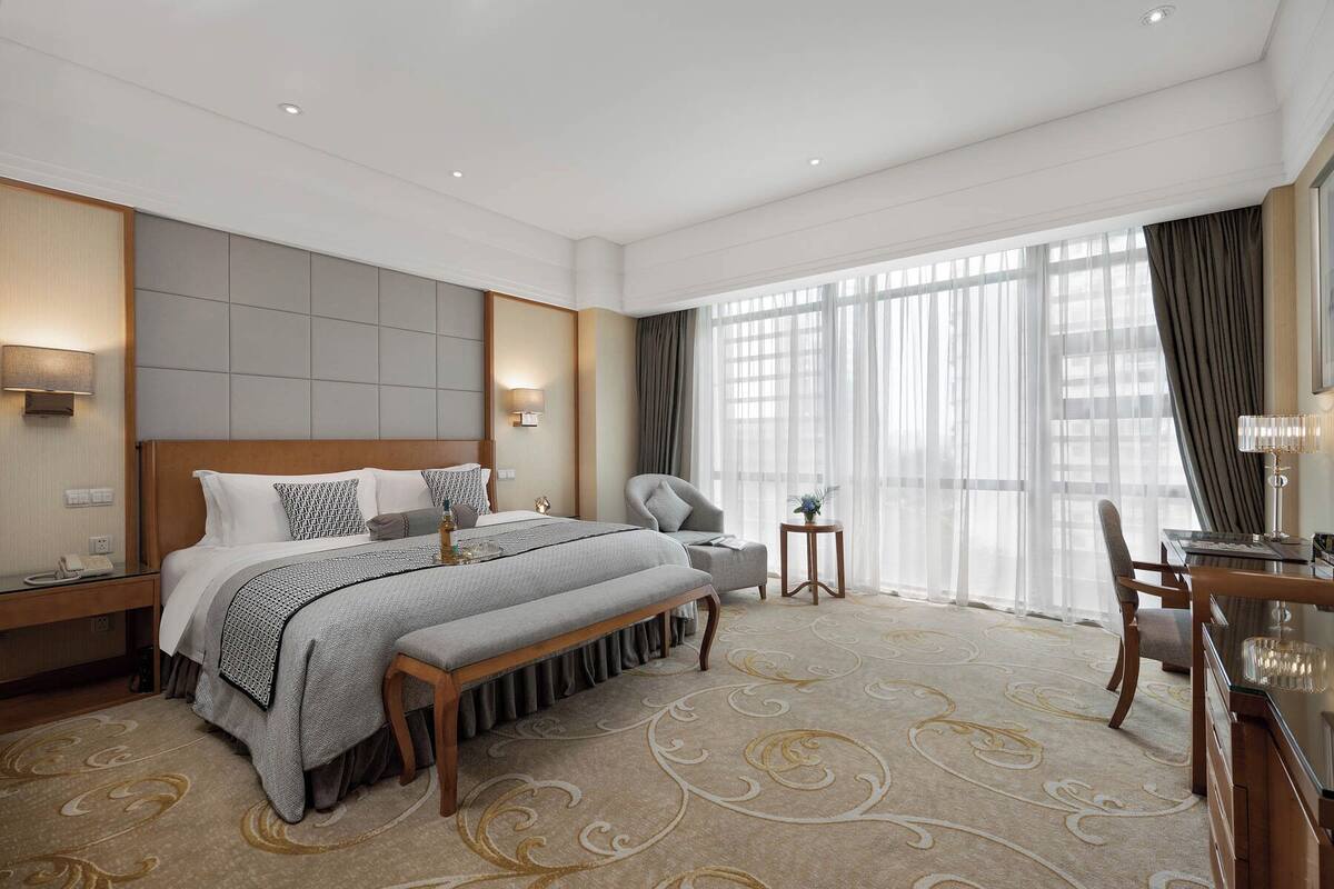 A modern hotel room with a large bed, bedside tables, a desk, and a chair.