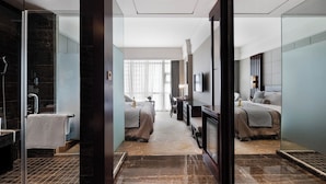 Una habitación de hotel moderna con una cama grande, un escritorio, un televisor y un baño con ducha y espejo.