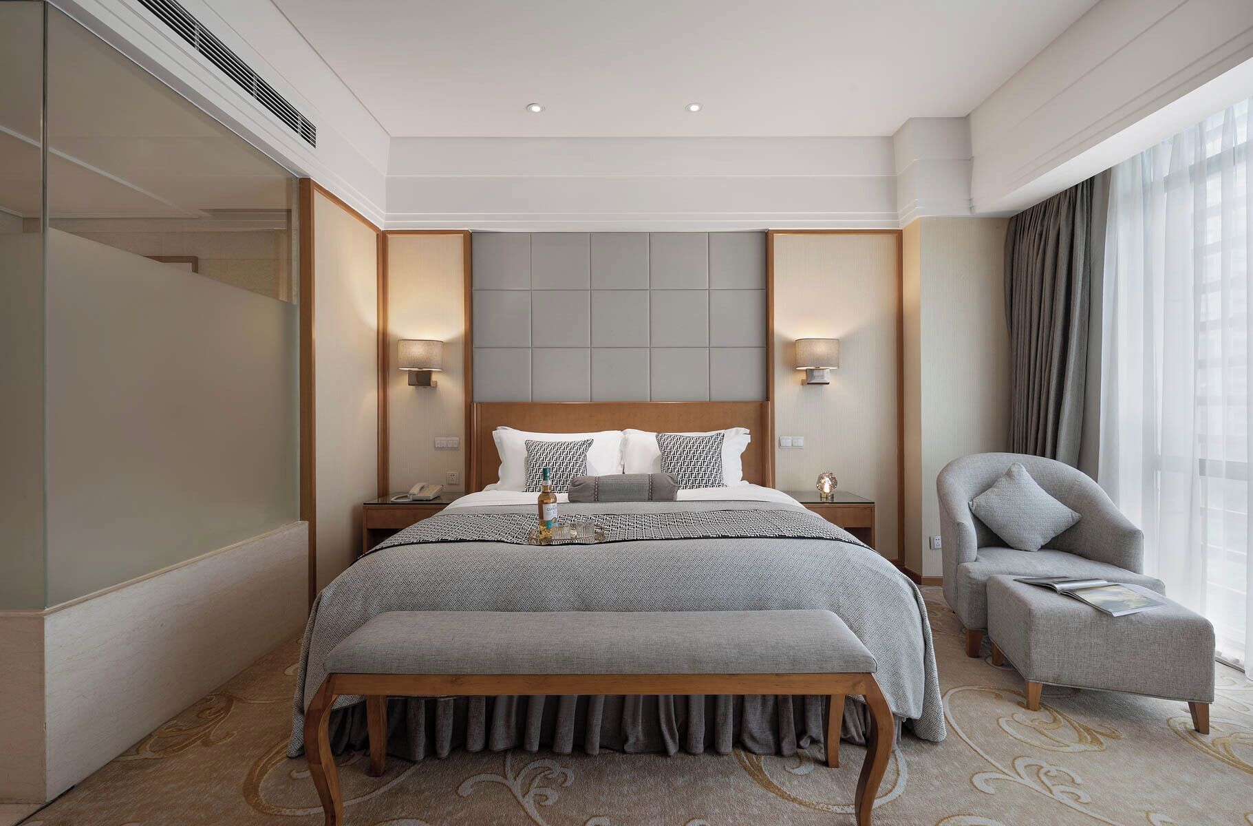 Une chambre d’hôtel moderne avec un grand lit, une table de chevet, une chaise et une fenêtre avec des rideaux.
