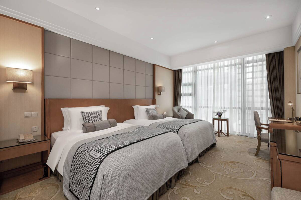 A hotel room with a large bed, two bedside tables, a desk, and a chair.