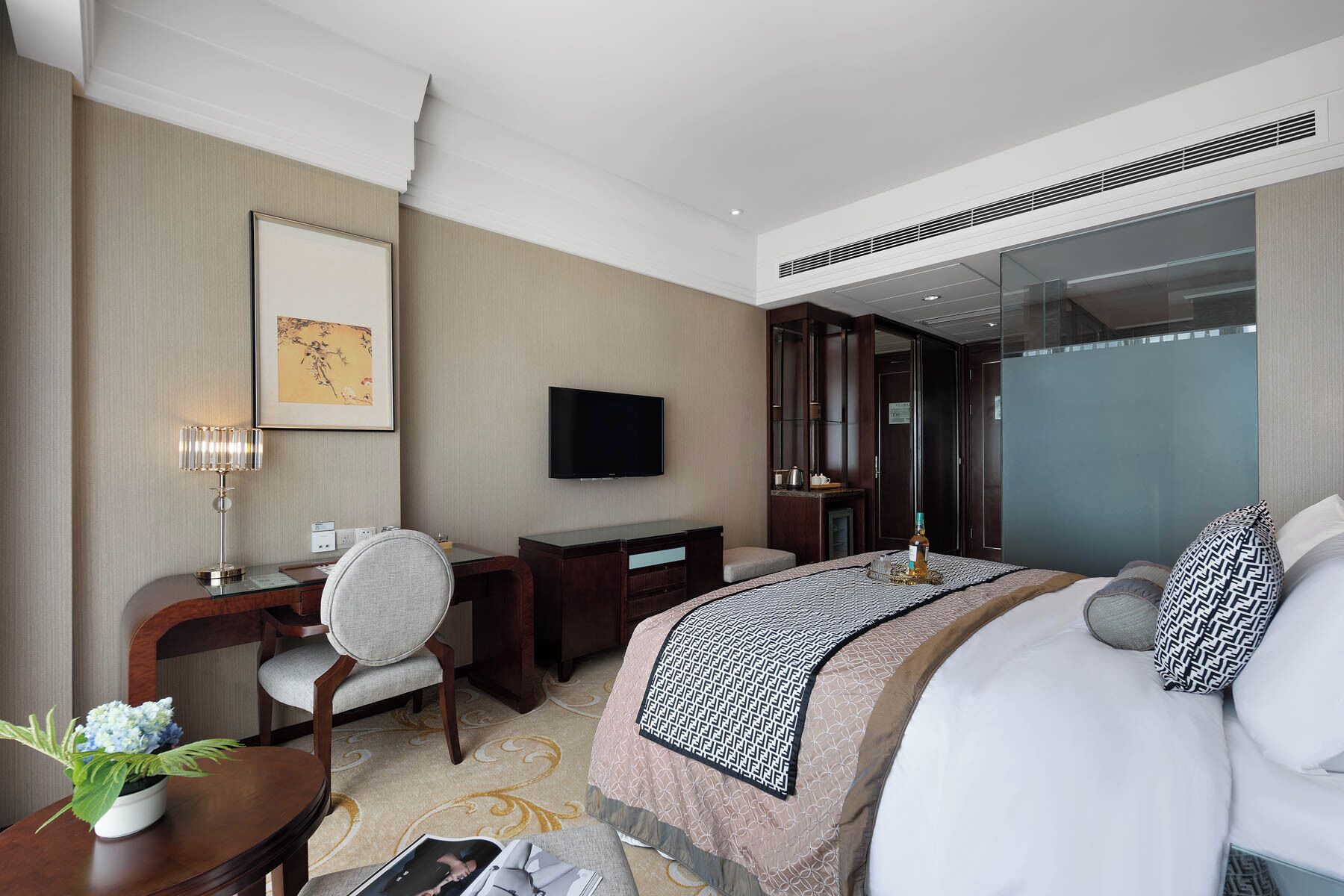 A hotel room with a bed, a desk, a chair, a television, and a large window.
