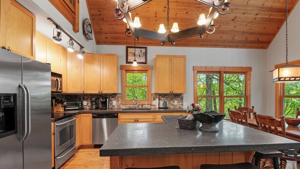 A modern kitchen with wooden cabinets, stainless steel appliances, and a large island with bar stools.