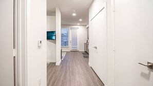 A hallway with a wooden floor, white walls, and a door leading to a room. - The Library - Comfy Studio Gym & Pet Friendly (Dallas)