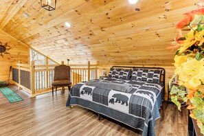 A wooden cabin bedroom with a bed, chair, and a view of the outdoors. - Creekside Cabin w/ Hot Tub: 7 Mi to Pigeon Forge (Sevierville)