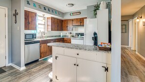 A kitchen with wooden cabinets, a white refrigerator, and a granite countertop.