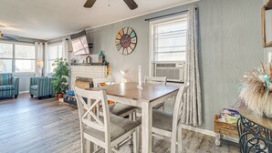 A dining area with a wooden table and chairs, a ceiling fan, and a clock on the wall.