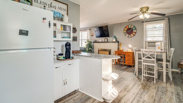 A modern kitchen with white cabinetry, a Midica refrigerator, and a breakfast bar.