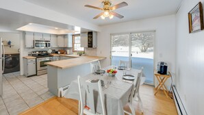 A modern kitchen with a central island, stainless steel appliances, and a dining area with a table set for four. - Deck & Fire Pit: Cozy Escape in Morrisville! (Morrisville)