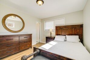 Une chambre à coucher avec un lit en bois, un grand miroir, une commode et une table de chevet avec une lampe.