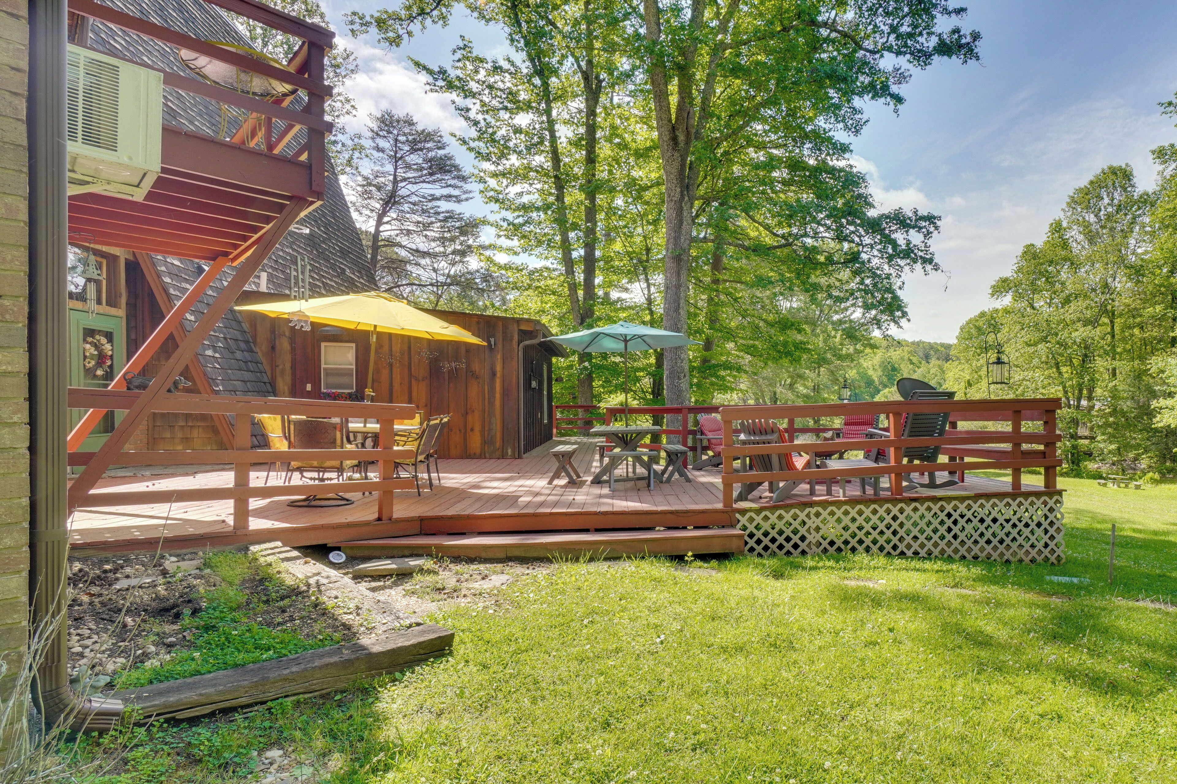 A wooden deck with outdoor furniture, a covered seating area, and a wooden staircase.
