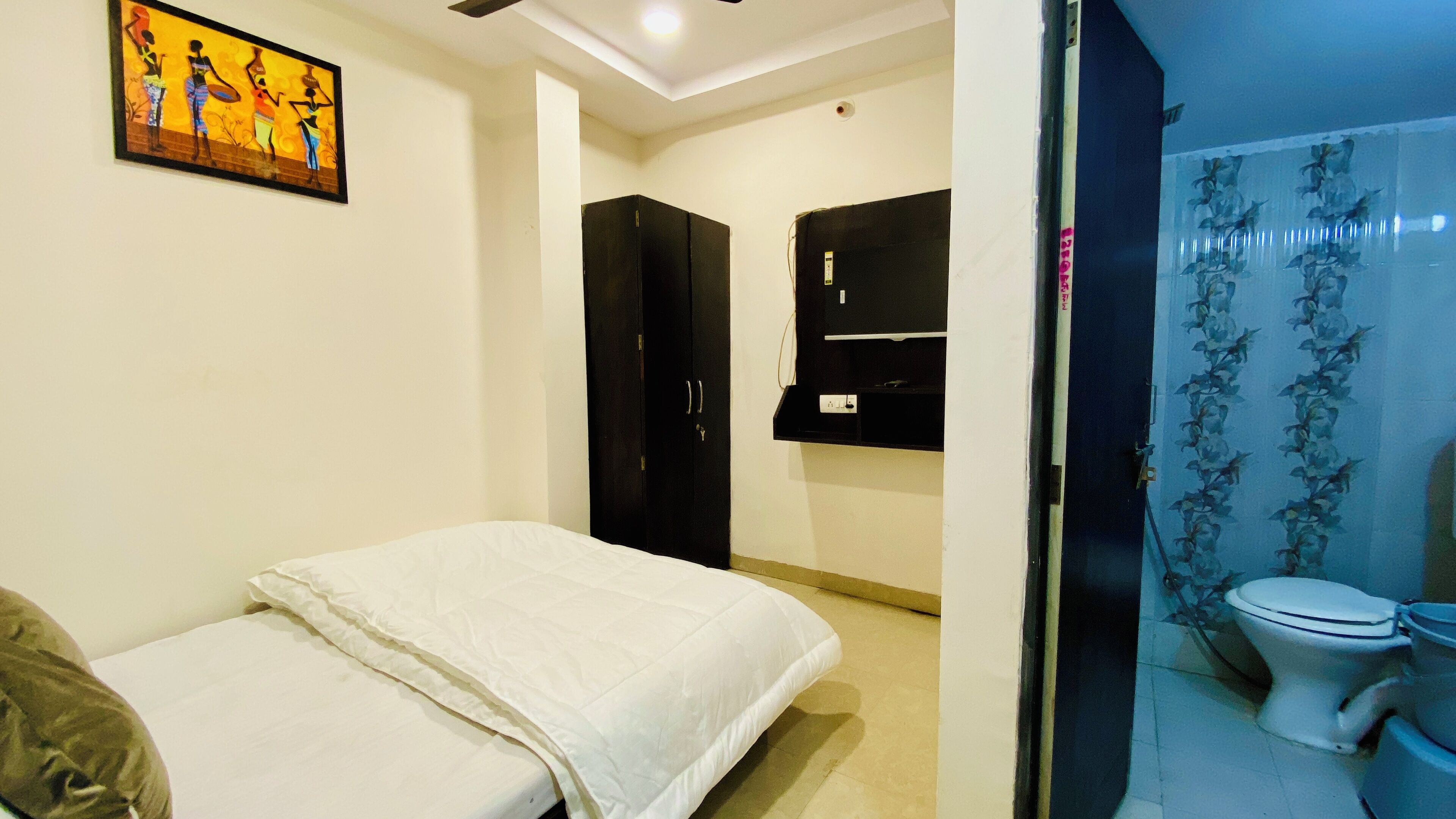 Un dormitorio con cama, armario y baño con inodoro y ducha.
