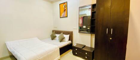 A bedroom with a bed, a wardrobe, a bedside table, and a wall-mounted mirror.