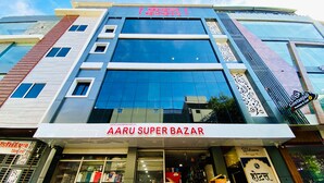 Un edificio de varios pisos con un amplio frente de vidrio y letreros que indican 'AARU SUPER BAZAR'.