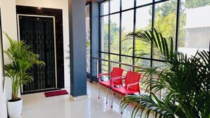 Un interior moderno con un ventanal grande, una silla roja y plantas en macetas.