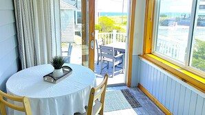 Une pièce avec une table ronde, une chaise, une porte donnant sur l’extérieur et une fenêtre avec vue sur l’extérieur.