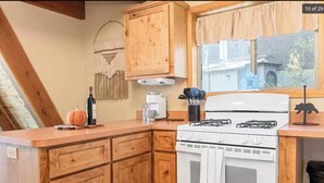 A kitchen with wooden cabinets, a white stove, and a window with a view of a house. - Charming A-Frame home,  wood fireplace,  7 miles to The Village and ski resorts. (Sugarloaf)