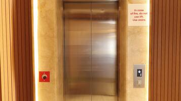 An elevator with a sign advising to use stairs in case of fire.