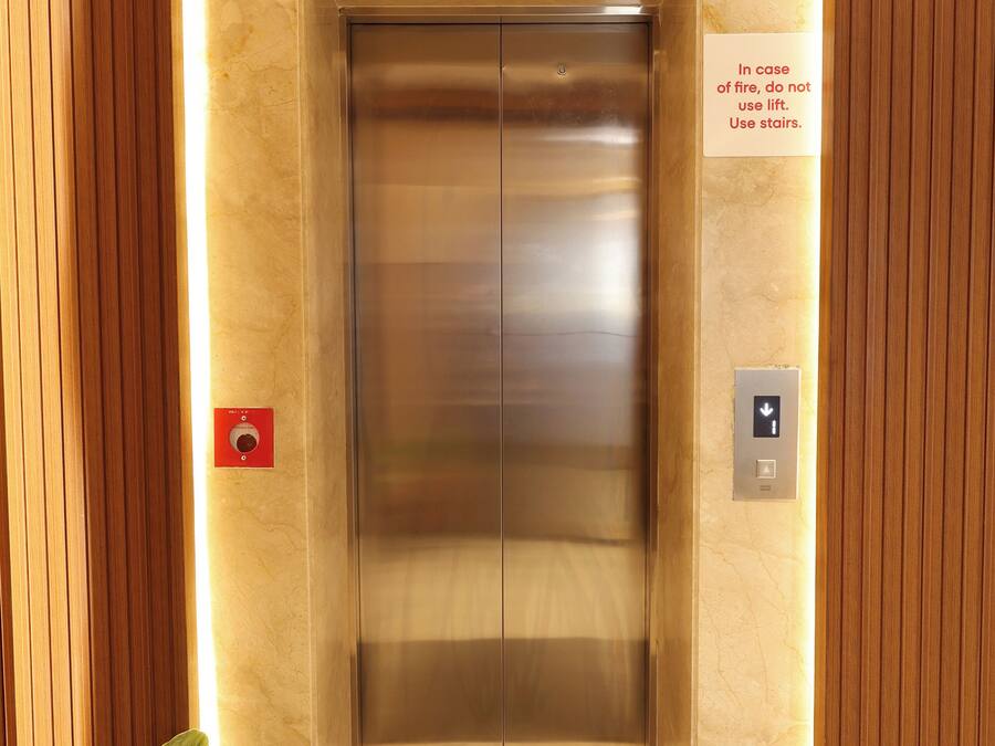 An elevator with a sign advising to use stairs in case of fire.