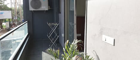 Un balcón con plantas en macetas, unidades de aire acondicionado y una puerta corrediza de vidrio.
