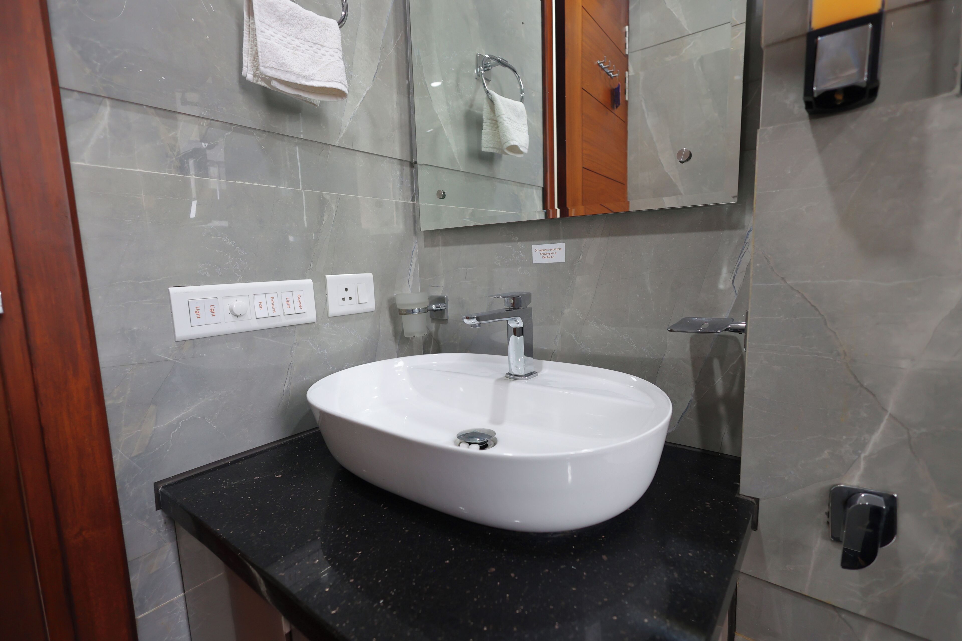 Un baño con un lavamanos blanco, un espejo y un perchero para toallas.