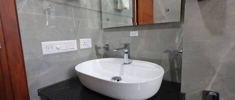 Un baño con un lavamanos blanco, un espejo y un perchero para toallas.