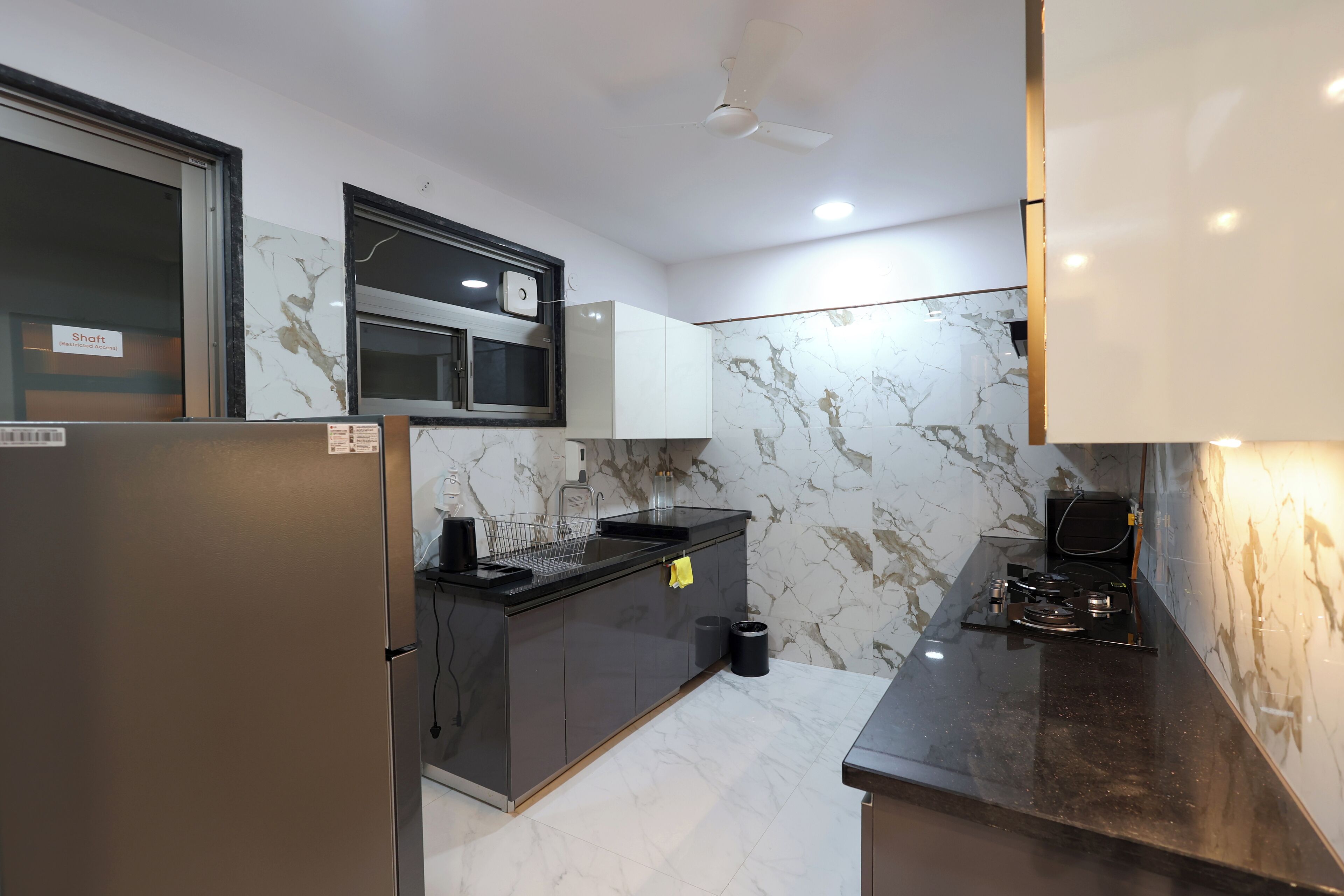 A modern kitchen with a built-in microwave, stainless steel appliances, and a marble backsplash.